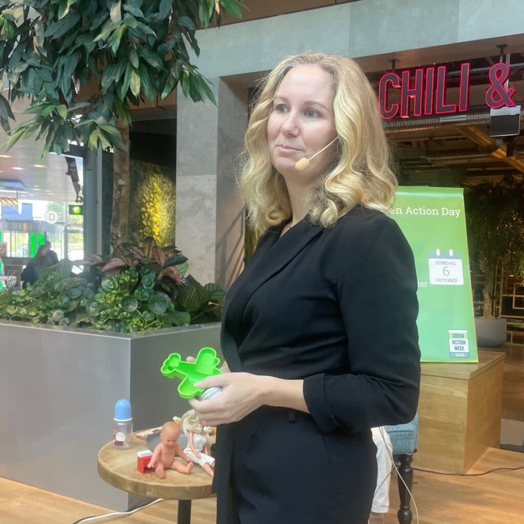 Kvinna som föreläser och visar upp en liten plastpryl.